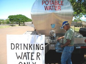 Kamu Enos fills a drinking water container at the temporary Kaunakakai Water Tanker.  Photo Courtesy County of Maui.