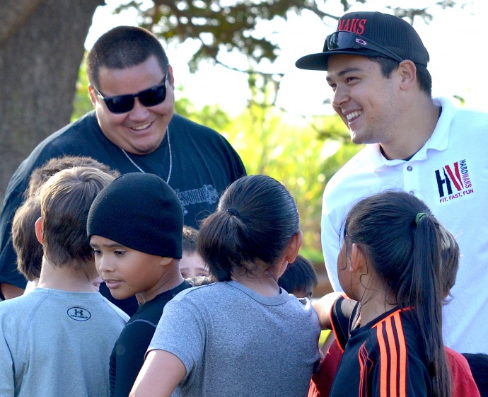 Cody Nakamura (right) and Kai Maiava (left) share a laugh with the grade-school campers Saturday following their one-hour session at Maui Tropical Plantation field. Photo by Rodney S. Yap.