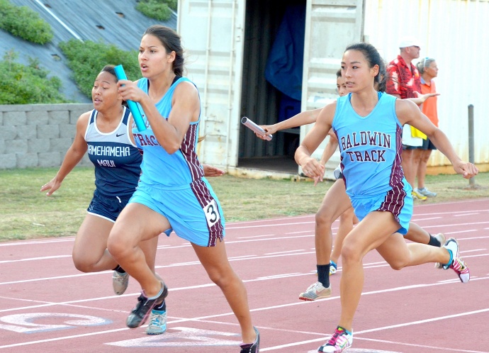 Baldwin High's Thyna Guedes takes the baton from teammate Amber Kozaki en route to winning the 4x100 relay. Photo by Rodney S. Yap.