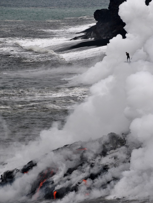 Do not be misguided by the risky actions of this person (upper right), who is standing on an active lava delta that could collapse without warning, amidst a plume of superheated steam, hydrochloric acid, and tiny particles of volcanic glass.  To avoid these ocean entry hazards, HVO advises staying at least 400 m (one-quarter mile) from where lava enters the sea. Photo courtesy Hawaiian Volcano Observatory.