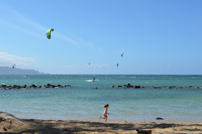 A kite surfer appears to be heading for the break in the rockwall at Ka'a Point, as children play nearby. Photo courtesy of Philip Botek.