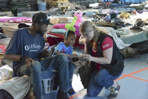 March 14, 2016. Monroe, Louisiana. After 4-year-old Anthony Cooks, Jr., showed Red Cross worker April Phillips his stuffed dog, she knew just the thing to put a smile on his face – videos of her own dogs. Volunteers pay special attention to children affected by disasters like the Louisiana floods. Special touches, such as sharing videos, playing games and sometimes even making balloon hats, help to make a very difficult experience as comfortable and normal as possible for the children and families. Photo by Daniel CIma/American Red Cross