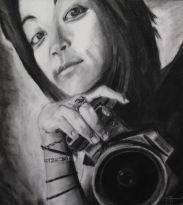 Second Place: Tanner Morrin, H.P. Baldwin High School, 12th grade Title: Tiny Inspiration (Woman holding Nikon Camera) Medium: Charcoal