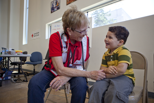 Nicolas Zipperer, 4, shows nurse Sharon Gettman, an American Red Cross volunteer, his “owie,” covered in a bandage. Nurse Gettman counsels the young Peeples Valley resident through his pain, assuring him that his “owie,” like the wildfire conditions, will feel better in time. She offers medical attention to any affected people in need at the local Red Cross shelter in Prescott, Arizona.   Tuesday, July 3, 2013, Prescott, Arizona. At the local Red Cross shelter in Prescott, Arizona Photos by Talia Frenkel.