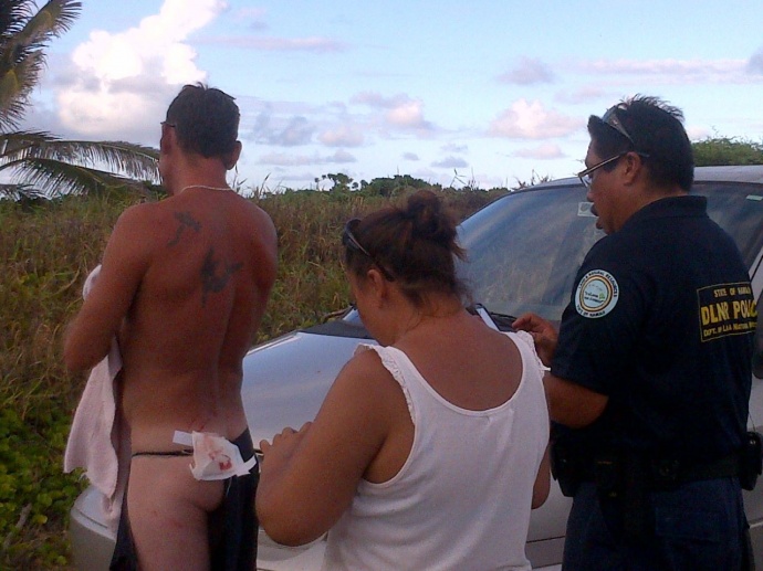 DLNR officers take a look at the apparent shark bite wound. Photo by Wendy Osher.
