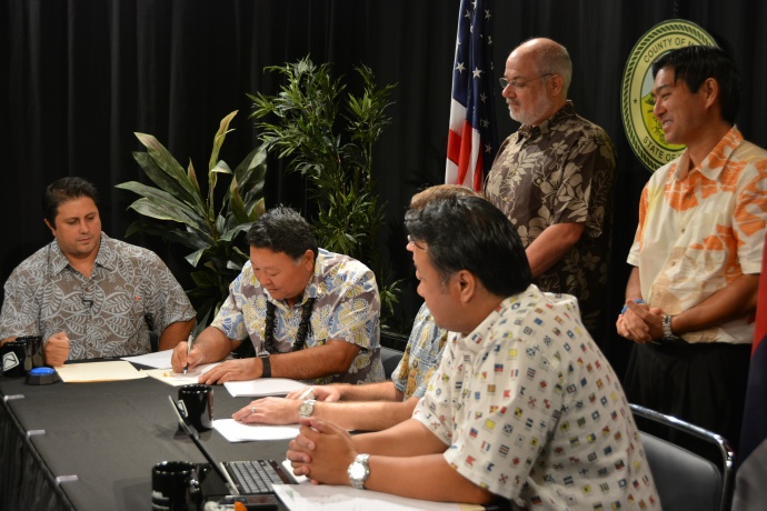 Mayor Arakawa signing the agreement at the Akakū studio in Kahului. Seated from left to right: Communication Director Rod Antone, Mayor Alan Arakawa, Managing Director Keith Regan (hidden), Chief of Staff Herman Andaya. Standing in the back observing are Anaergia Director of Business Development Karl Bossert and Maui County Department of Environmental Management Director Kyle Ginoza.