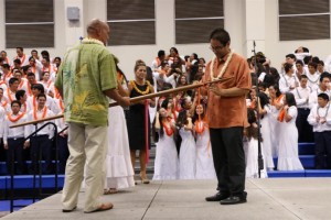 Vice Principal, Leo Delatori ties the winning class color on the ihe as Lance Cagasan (holding the ihe) and Jay-R Kaawa, High School Principals look on.  Photo courtesy, Lokelani Patrick/KSM