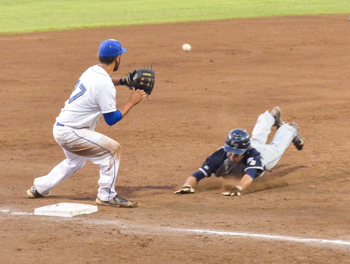 Kamehameha Schools Maui center fielder Cal Alexander slides safely into third base ahead of the tag by Maui High third baseman Kody Medeiros. Photo by Rodney S. Yap.