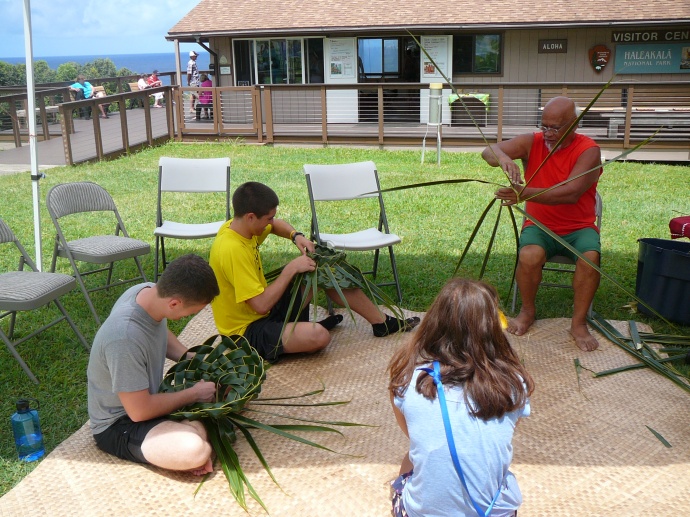Bolly Helekahi helps a visitor make a coconut leaf hat. Photo credit: Haleakalā National Park.