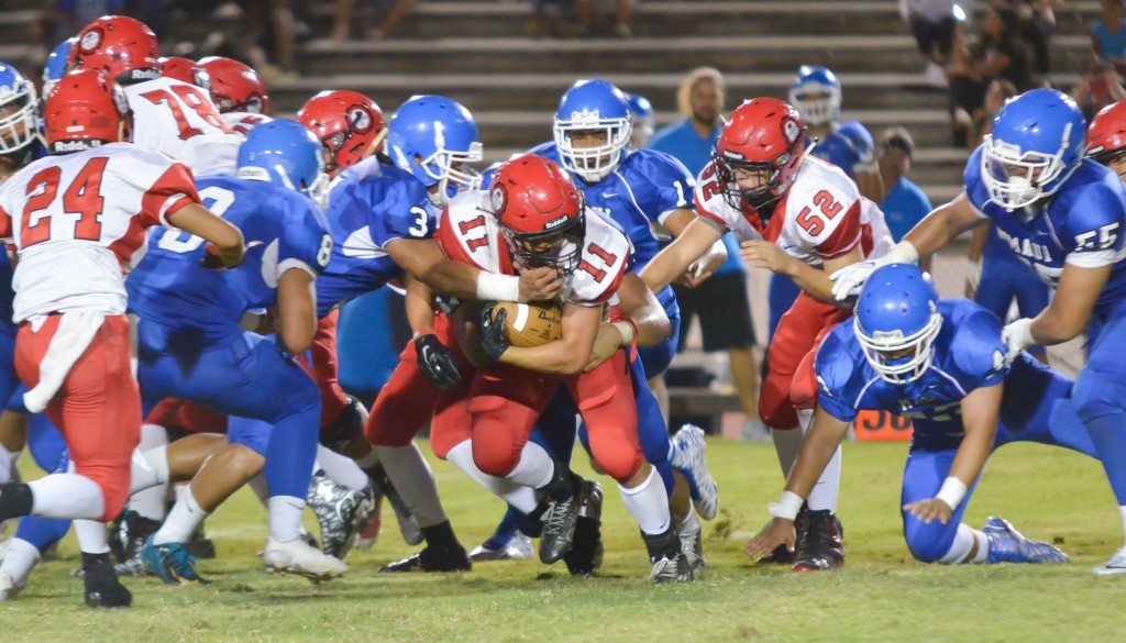 Lahainaluna's Justice Tihada (11) is wrapped up by the Sabers' defense, led by Hanisi Lotulelei. Photo by Rodney S. Yap.