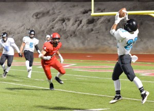 King Kekaulike's Brandon Soriano (22) squeezes this pass from quarterback Cameron Russell (5). Photo by Rodney S. Yap.