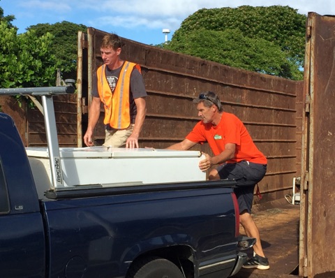 Rich Lynch (left) and Peter Faust help unload a refrigerator