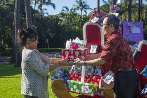Joyce Natividad, Program Secretary for Maui Child & Family Services receives the annual donation of gifts by the Mākena Beach & Golf Resort from Kiyoshi Terada (right), sales & marketing coordinator at Mākena Beach & Golf Resort. 