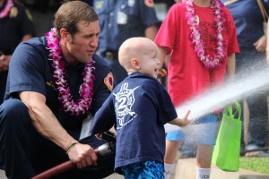 Trucker Dukes shooting water with his dad, firefighter Joshua Dukes outside of the Kahului Fire Station. Photo by Wendy Osher.