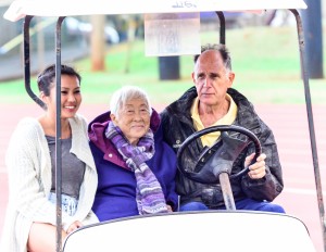The wife, Doris, of the late Satoki Yamamoto and grand daughter Aleysa Martin get a ride from Maui Track & Field Officials Association President Allan Fernandez right before being introduced to the crowd at Saturday's finals of the 63rd MIL Yamamoto Invitational track meet. Photo by Rodney S. Yap.