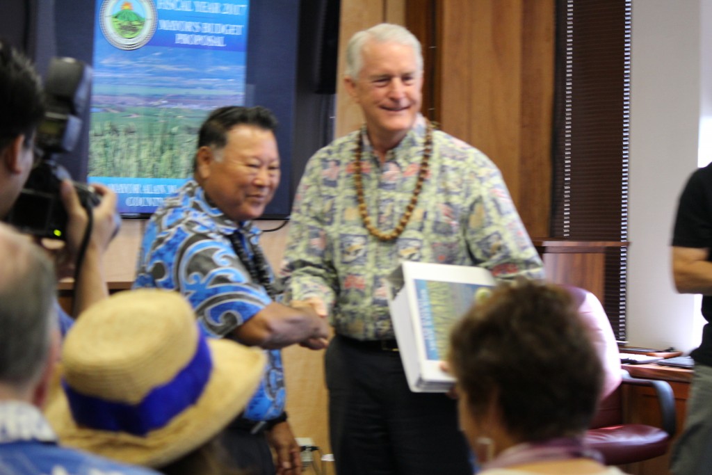 Maui Mayor Alan Arakawa (left) hands of the 920 page budget document to Maui Council Chair Mike White. Photo (3.24.16) by Wendy Osher.