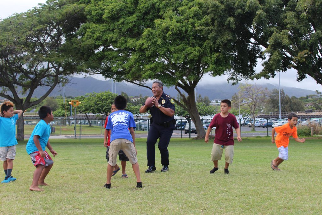 Maui Police Chief Tivoli Faaumu playing football with BGCM members. Photo credit: Boys & Girls Clubs of Maui.