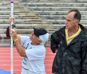 As head referee, Allan Fernandez signs off on all new records. Here he watches as pole vault official Gene Zarro measures the distance to the upright. Photo by Rodney S. Yap.