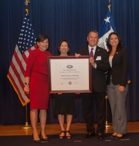 US Secretary of Commerce Penny Pritzker (left) and US Rep. Tulsi Gabbard presented the Hawai‘i Tourism Authority with the President’s “E” Award today in Washington, DC. Accepting the award was HTA President and CEO George D. Szigeti and HTA Director of Communications Charlene Chan. Photo credit: US Department of Commerce