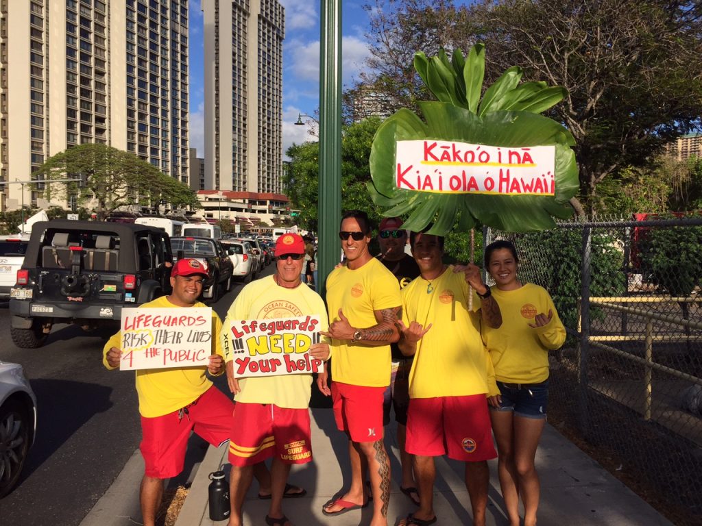 Hawaii Government Employees Association Unit 14 members (ocean/water safety and state law enforcement officers) and their supporters waved signs and rallied on Monday, May 9, along Ala Moana Blvd in a show of solidarity for their colleagues on Maui. The sign wavers are urging the Maui County Council to pass funding legislation for the Unit 14 arbitration decision that was finalized and awarded by an arbitration panel on February 22 of this year. Courtesy photo.
