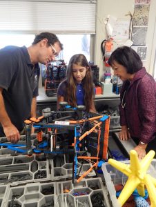 Maui Preparatory Academy instructor Branden Hazlet and student Violetta Thompson show Maui Electric President Sharon Suzuki a STEAM—STEM and Art—project.