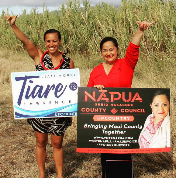 Aloha ‘Aina candidates Tiare Lawrence (left) and Napua Greig-Nakasone sign wave on a Valley Isle roadside Tuesday, June 28. They seek to represent Upcountry in the Hawai‘i state House and Maui County Council, respectively, and will appear at a candidates forum 6 p.m. Thursday, July 7, at Keokea Marketplace. Photo credit: Votetiare.com image votetiarte.com