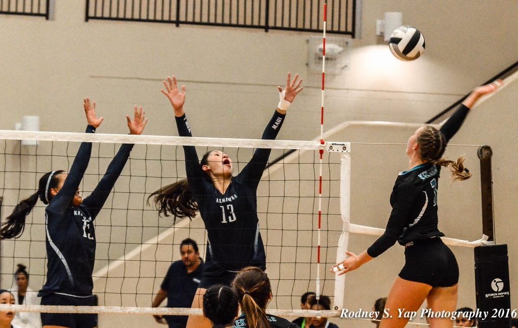 King Kekaulike junior outside hitter Chandler Cowell goes above the block of Kamehameha Maui’s Kylee Yamamshita (13) and Caylee Tuzon (15). Photo by Rodney S. Yap.