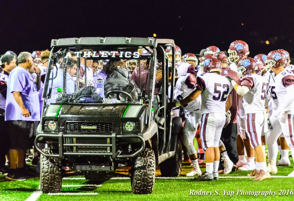 Baldwin players and coaches huddle around injured teammate Nainoa Keahi before he is carted off the field Saturday. Photo by Rodney S. Yap.
