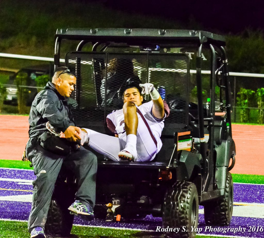 Baldwin linebacker Nainoa Keahi assures his teammates he will be fine one last time as he is carted off the field with school athletic trainer Scott Pagdilao assisting. Photo by Rodney S. Yap.