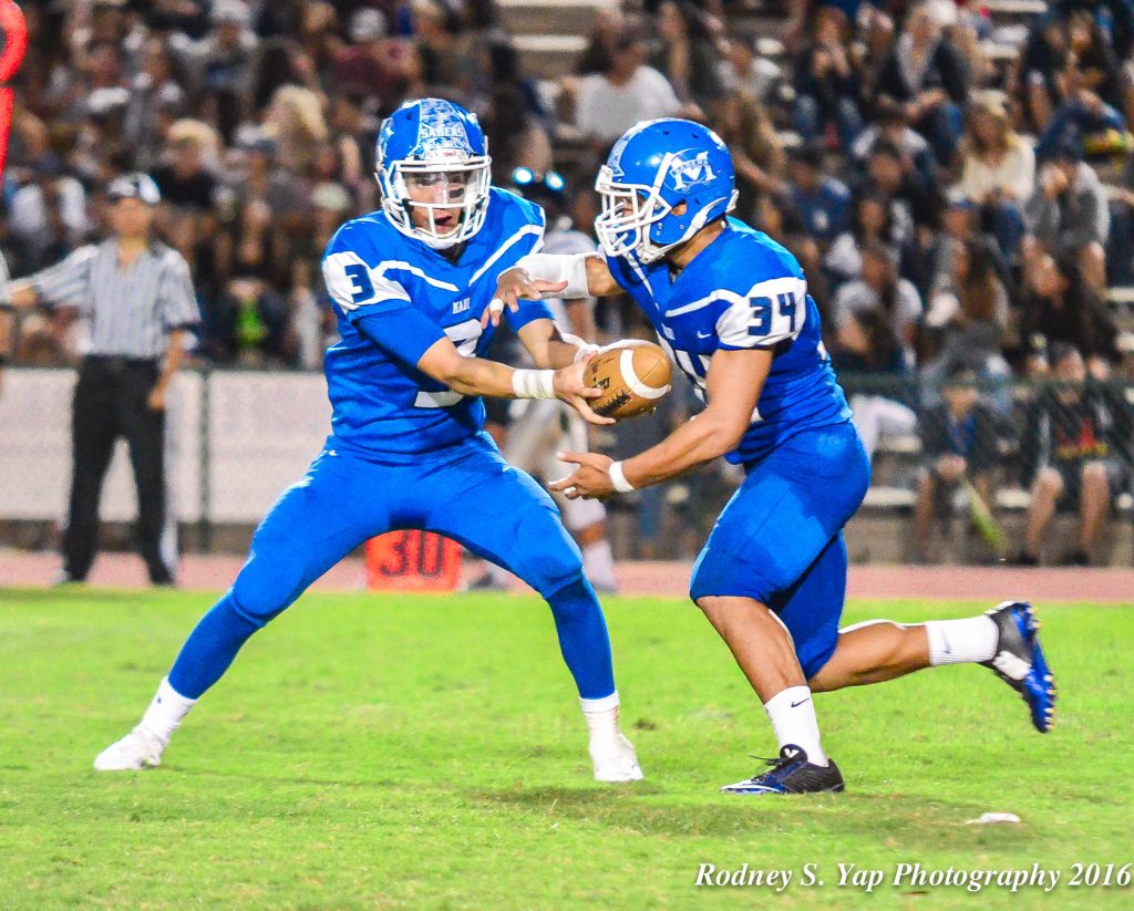 Maui High School's Hanisi Lotulelei (34) rushed for four touchdowns in the Sabers' 48-0 win at King Kekaulike on Saturday. Here Lotulelei is shown taking a handoff from quarterback John-Michael Mokiao-Duvachelle (3) during a game played last week. Photo by Rodney S. Yap.