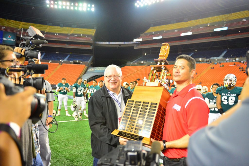 Lahainaluna co-head coach Garret Tihada holds the Division II First Hawaiian Bank State Championship Trophy after beating Kapaa at Aloha Stadium. Photo by Glen Pascual.