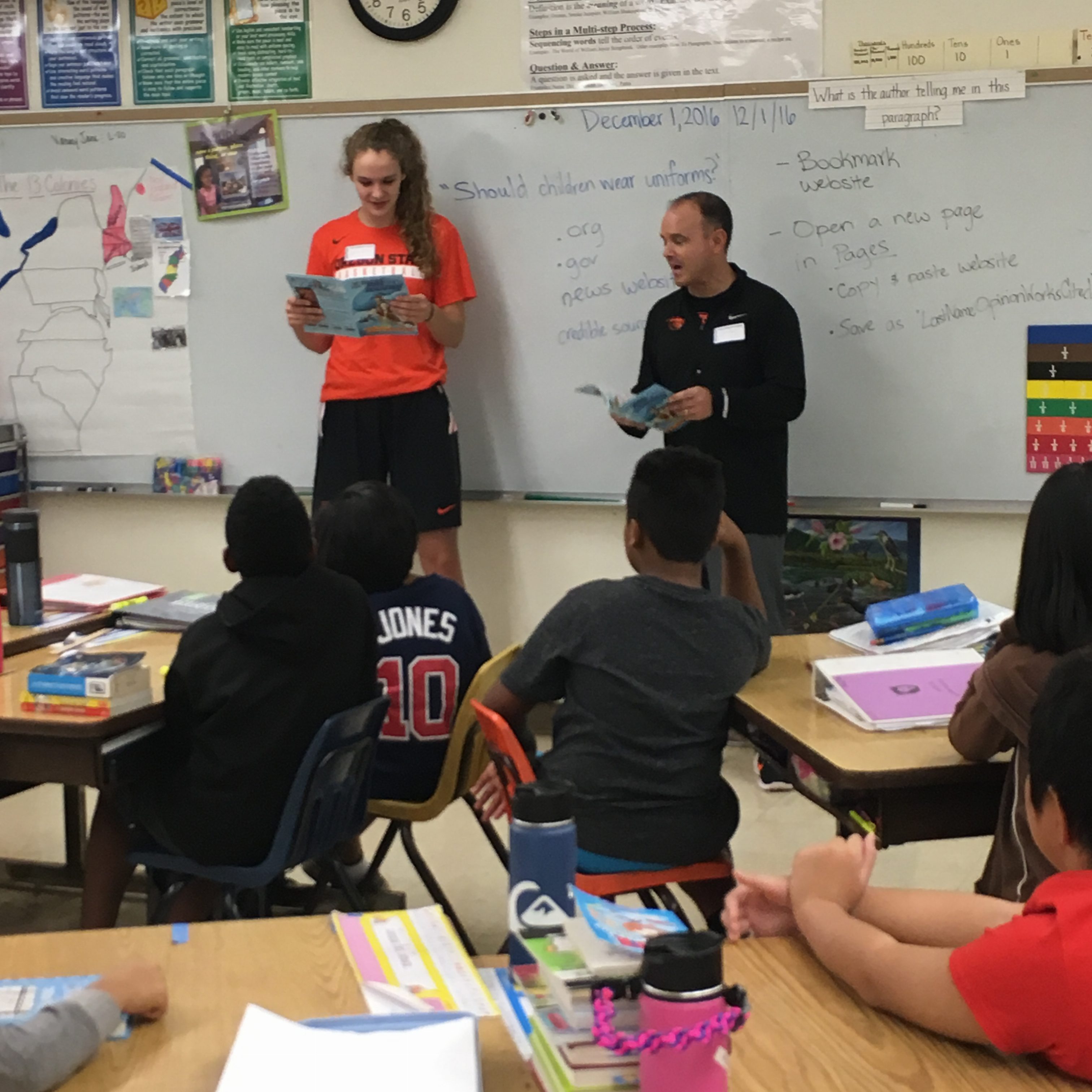 OSU’s visit to Kihei Elementary. Player #10 Katie McWilliams and Head Coach Scott Rueck reading Dunk Champion’s Kenny Dobbs’ comic book. PC: basketballMAUI